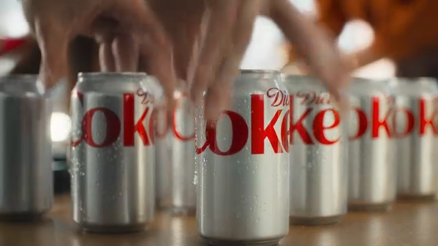 A close-up of a hand holding a chilled Diet Coke