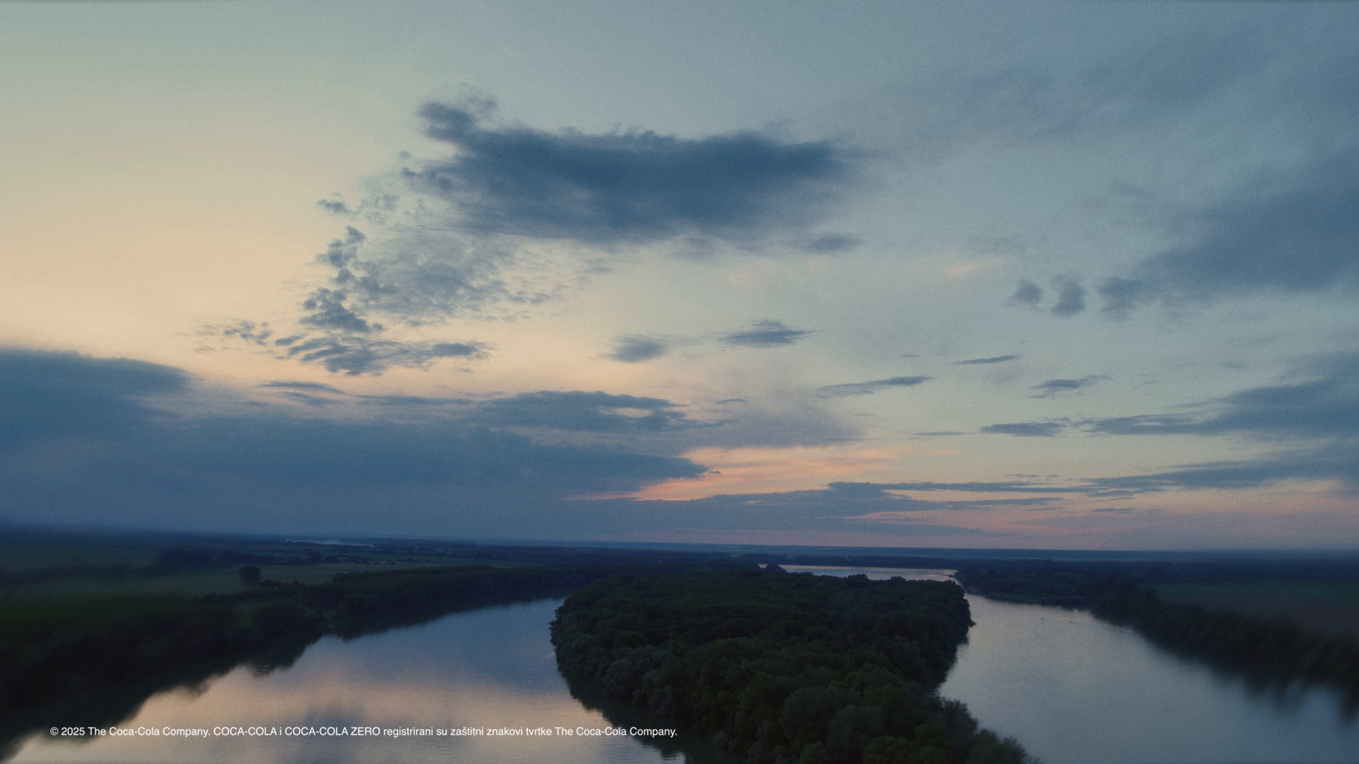 Rijeka Dunav pri zalasku sunca, s mirnim vodama i oblačnim nebom.